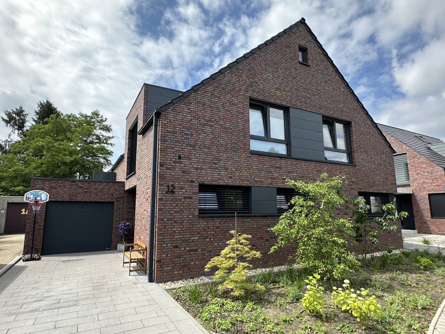 Massivhaus mit brauen-rotem Klinker und dunklen Fenstern