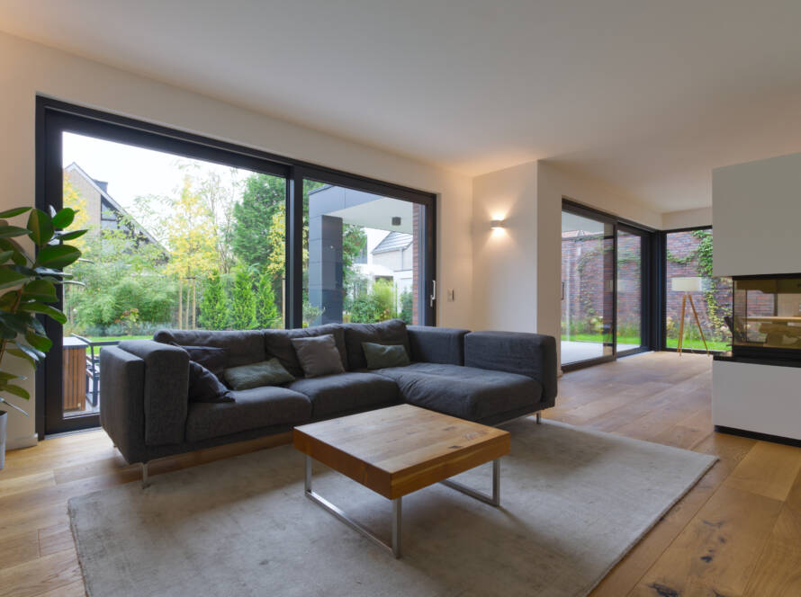 Dunkles Ecksofa mit Kamin und großer Fensterfront im Hintergrund