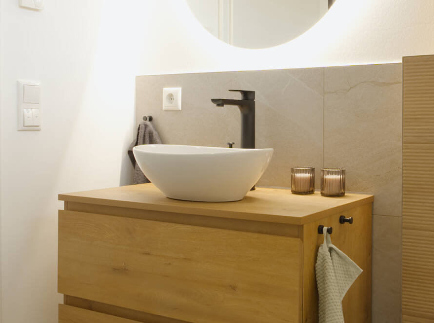 Waschbecken mit Holzunterschrank und rundem Spiegel