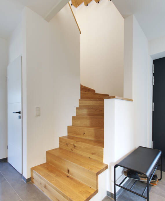 Eingangsbereich mit dunkler Haustür und einer Holztreppe