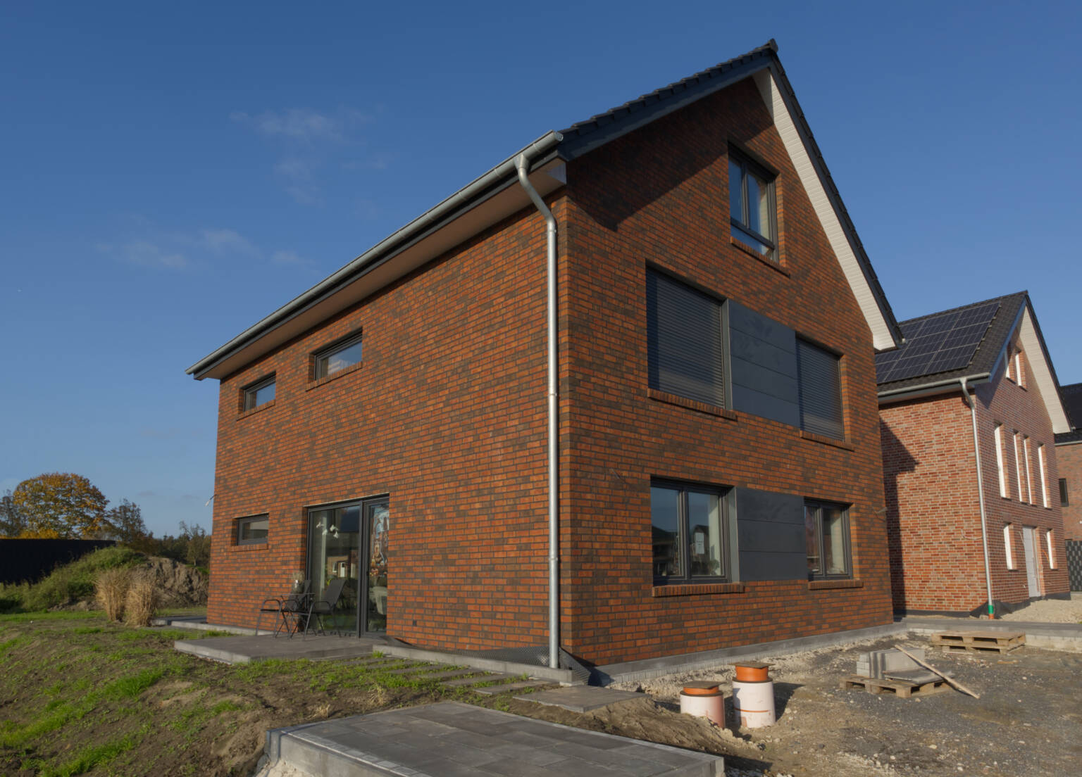 Massivhaus mit braunem Klinker und dunklen Fenstern
