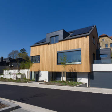 Massivhaus mit Holzfassade und großen Fenstern und Doppelgarage
