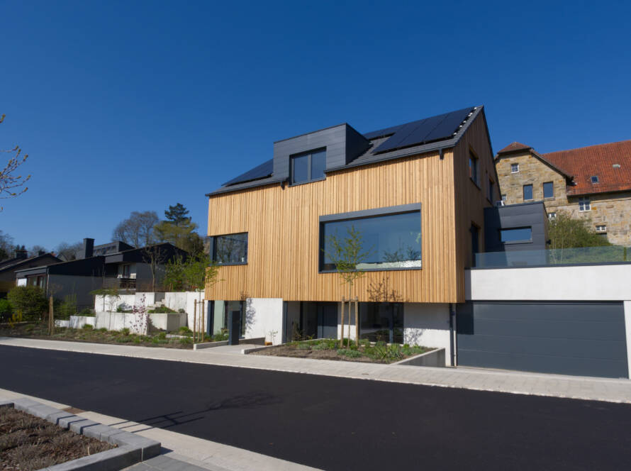 Massivhaus mit Holzfassade und großen Fenstern und Doppelgarage