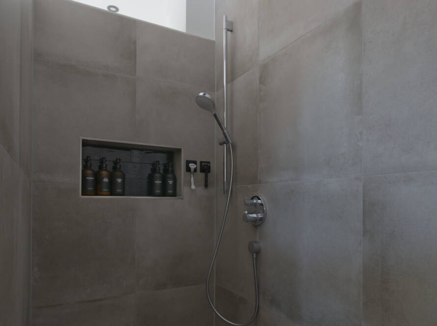 Bodentiefe Dusche mit gemauerten Wänden, grauen Fliesen und Chrom-Unterputzarmaturen