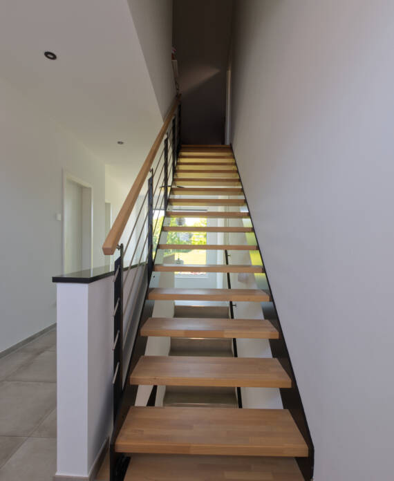 Moderne Wangentreppe mit schwarzen Wangen und geraden Holzstufen und einem Handlauf aus Holz
