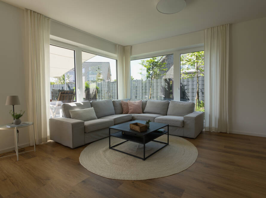 Helles Ecksofa mit großer Fensterfront im Hintergrund