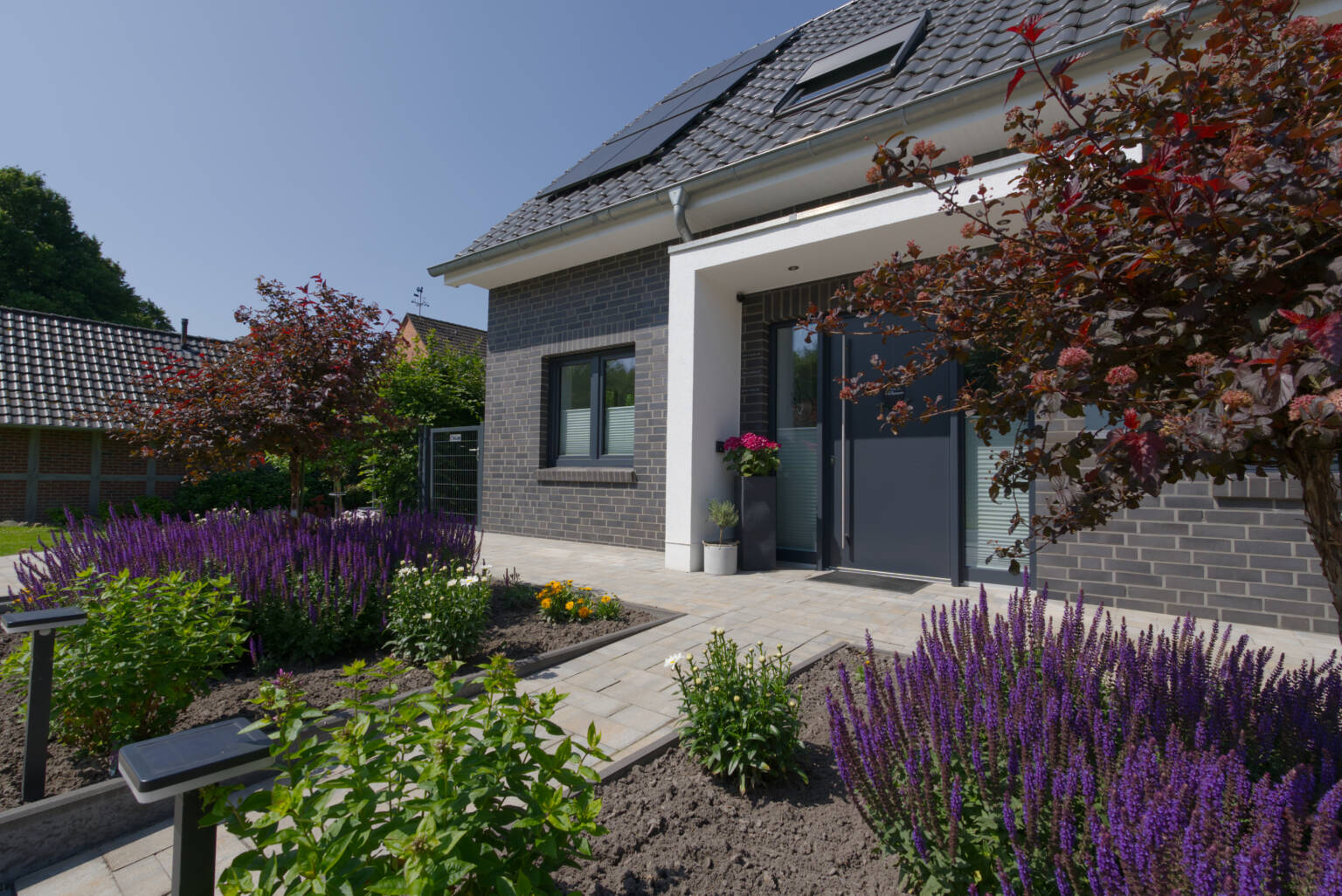 Vorgarten mit Blumen und Büschen eines Einfamilienhauses