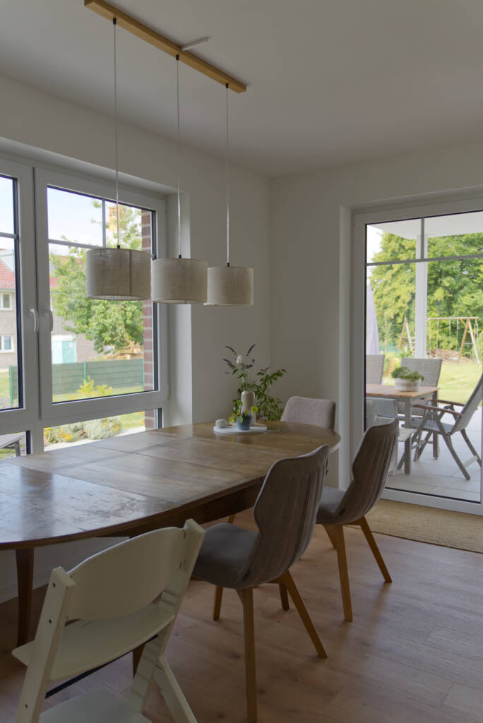 Esstisch mit Deckenlampe und Fenstern im Hintergrund