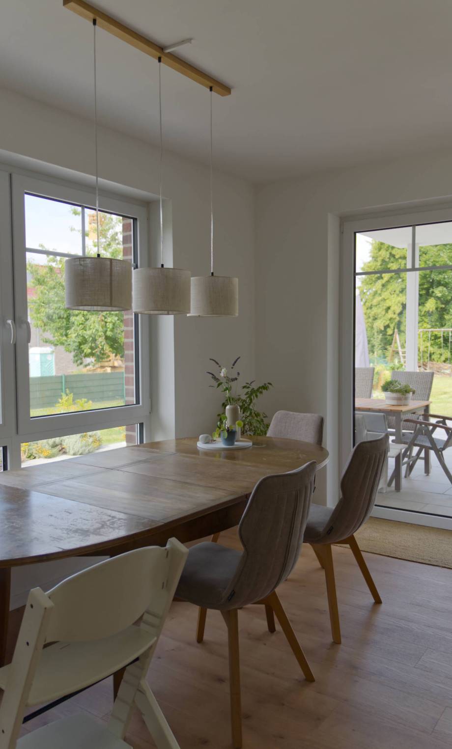 Esstisch mit Deckenlampe und Fenstern im Hintergrund