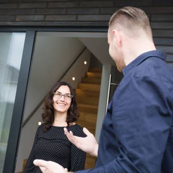 Mann spricht mit dunkelhaarigen Frau an der Haustür
